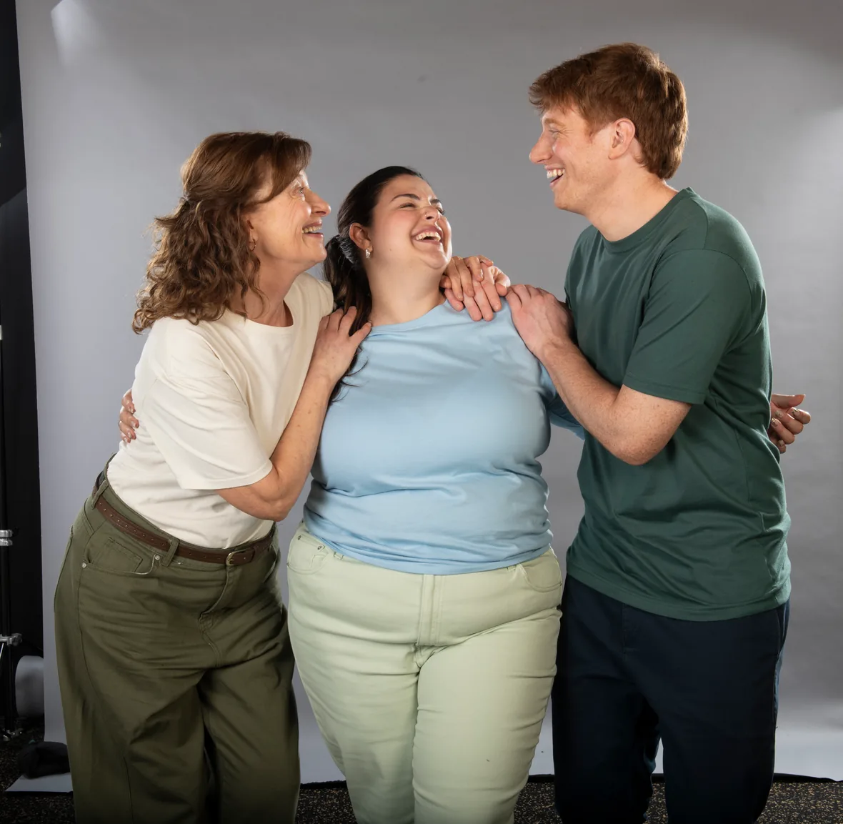 Tres personas abrazadas, riéndose